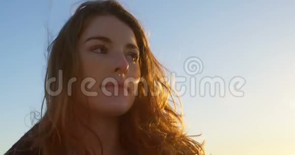 日落时分海滩上一位体贴的漂亮女人的特写镜头视频的预览图