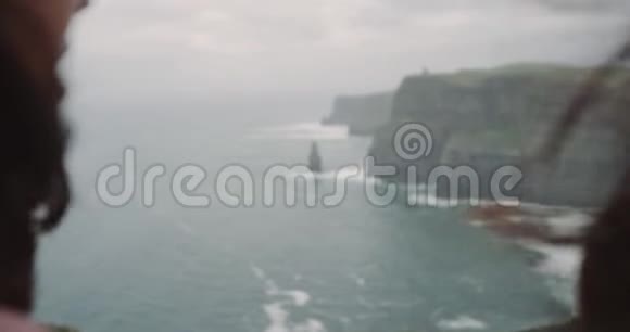 两位年轻女士在悬崖顶上背对着镜头双手望着大海露出一颗大心脏视频的预览图