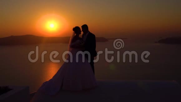 希腊日落圣托里尼屋顶上的新婚夫妇视频的预览图