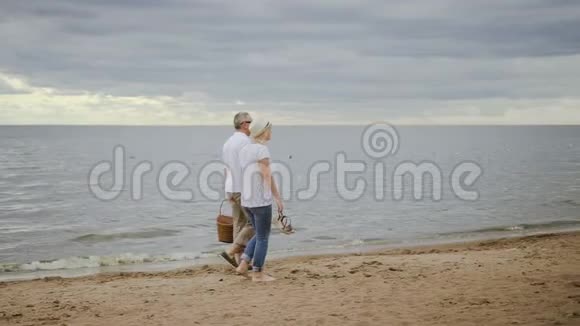 浪荡成熟的一对夫妇在海洋海岸线上散步视频的预览图