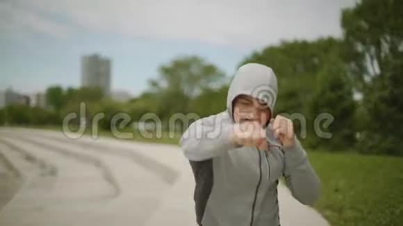 一个年轻的运动员在城市和湖泊的背景下训练拳击运动慢动作中弹视频的预览图