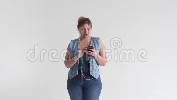 胖女人用手机耳机听音乐视频的预览图