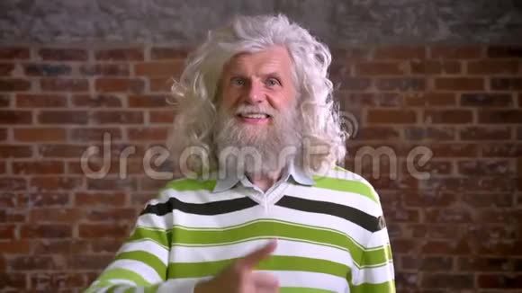 斯迈利不寻常的现代老人留着白大胡子兴高采烈地站在砖房里现代的景色视频的预览图
