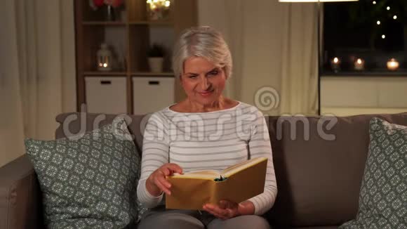 快乐的老年妇女晚上在家看书视频的预览图