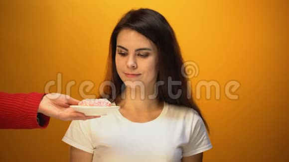 美丽的女孩吃甜甜圈代替苹果糖瘾不健康的零食视频的预览图