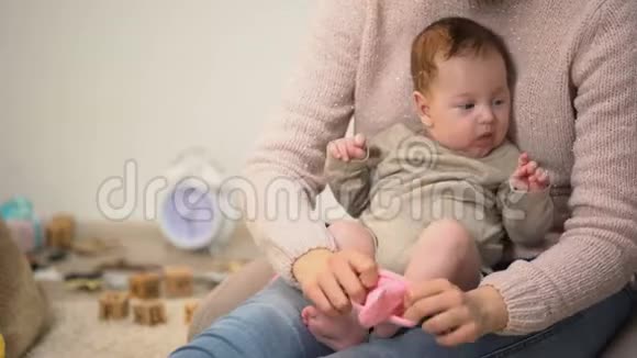 妈妈把粉红色的袜子穿在可爱的女婴身上新生的衣服和配饰上视频的预览图