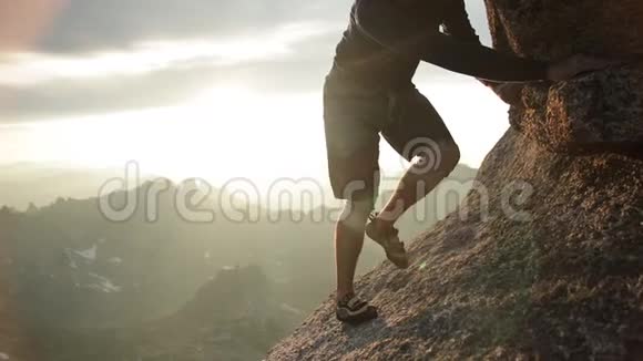 日落时攀登岩石的人的腿视频的预览图