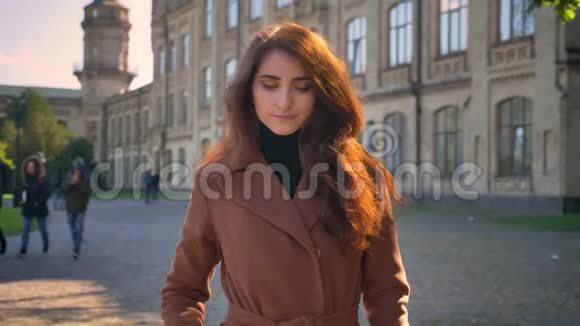 美丽的白种人女性站在古城的上空在阳光下抚摸着她的棕色卷发视频的预览图