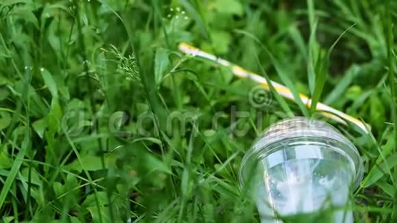 塑料杯躺在森林里的草地上污染视频的预览图