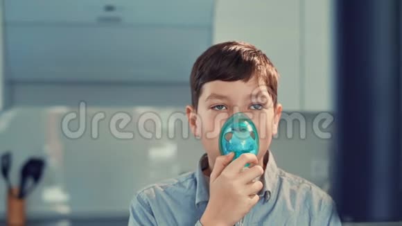 治疗哮喘男孩通过吸入器呼吸站在厨房里视频的预览图