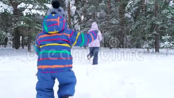在寒冷的冬天一个小孩子在雪地森林或公园里追赶他的母亲休闲体育和游戏视频的预览图