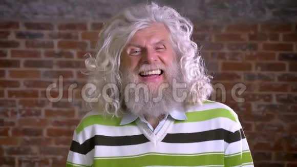 滑稽的白种人爷爷笑着长着牙齿白灌木和长胡子现代的站立男砖墙视频的预览图