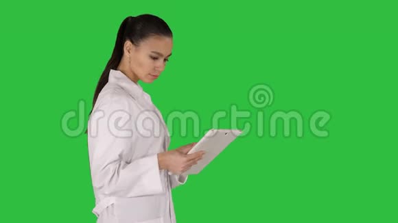 女医生使用平板电脑和行走在绿色屏幕铬键视频的预览图
