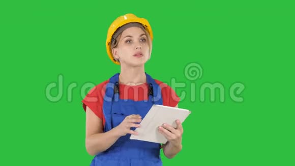 女工程师检查触摸板上的建筑计划看物体她周围的建筑在绿色屏幕上Chroma视频的预览图