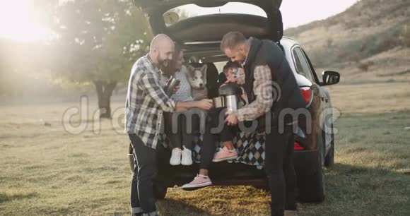 在一个阳光明媚的日子里两个家庭带着一个小孩子和一只哈士奇狗在大自然中间野餐他们停下来了视频的预览图