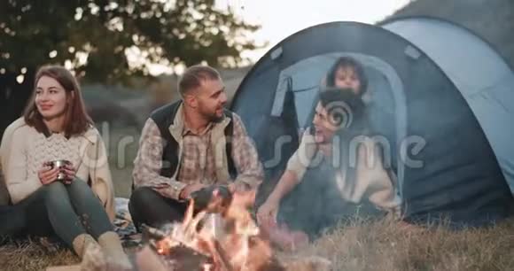 美丽的年轻家庭有一个小男孩和他们的朋友在大自然中间的帐篷野餐他们很高兴视频的预览图