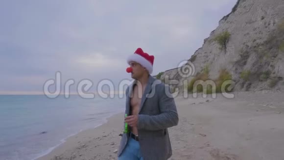 一个独身的人在海滩上戴着红鼻子和圣诞帽视频的预览图