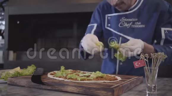 一个穿着厨师制服的人在准备用拉瓦什包装的美味菜肴厨师手拿白色橡胶手套撕生菜叶和视频的预览图