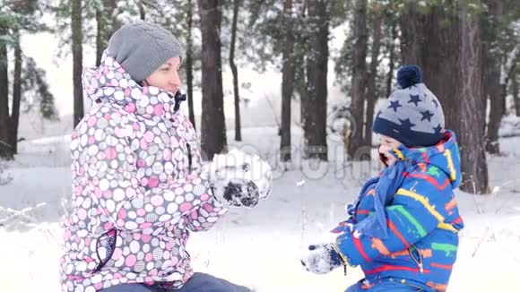 快乐的母亲和孩子在雪地里玩耍在冬天的森林或公园前坐着把它扔起来光冷视频的预览图