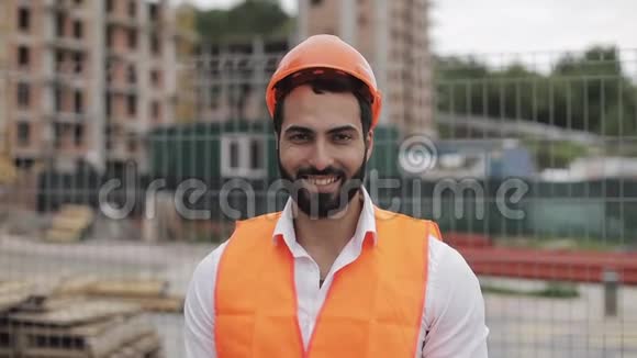 施工工人戴着橙色头盔对着镜头微笑的肖像建筑工人站在视频的预览图