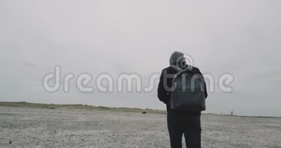 在寒冷的天气里在海边一个快乐的人在一场雨后穿过灰色的海滩视频的预览图