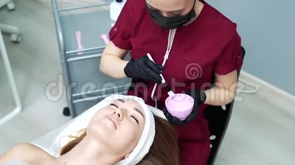 美容师在一个年轻女人的脖子和脸上涂化妆品视频的预览图
