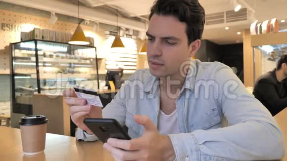 青年男子在咖啡厅网上购物智能手机付款视频的预览图