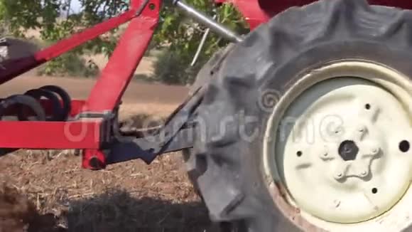 红色拖拉机与犁耕田土近景在缓慢的运动视频的预览图