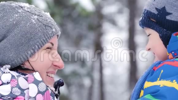 美丽的笑脸特写一位快乐的母亲在冬天白雪覆盖的森林或视频的预览图