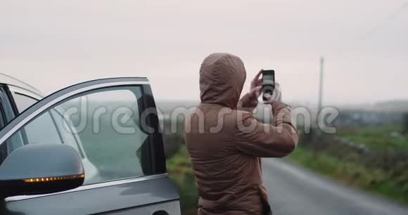 游客停下来车停在乡间的路中间拍一些日落的照片令人惊叹的风景视频的预览图