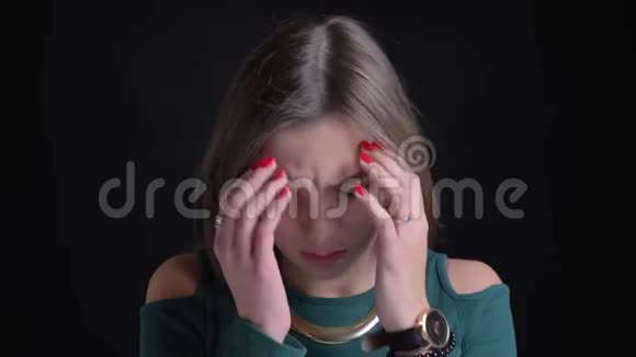 一位年轻的黑发白种人女孩因头痛和在黑色皮肤上做按摩而特写视频的预览图