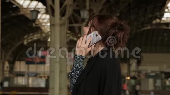 漂亮的中年黑发女人在火车站用手机视频的预览图