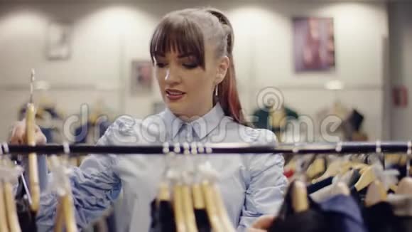 一位漂亮的年轻女子在服装店的货架上看到一条裙子视频的预览图