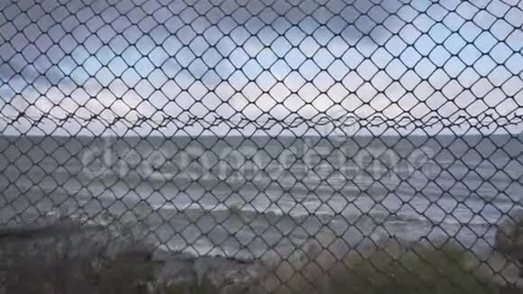 透过金属网观看美丽的海岸线海浪落在海岸上视频的预览图