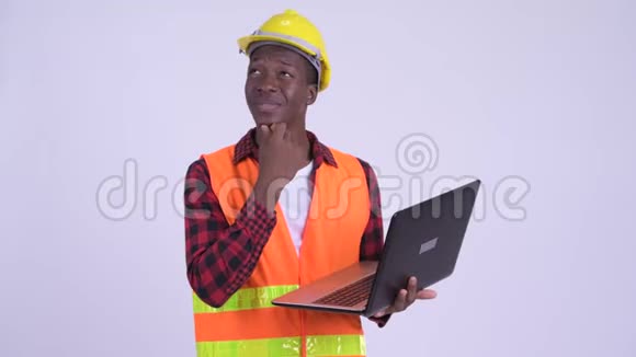 年轻快乐的非洲男性建筑工人思考使用笔记本电脑视频的预览图