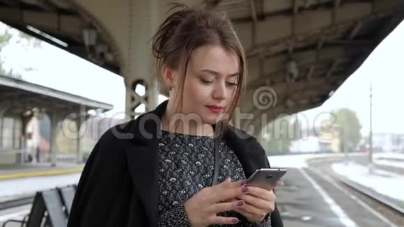漂亮的中年黑发女人在火车站用手机视频的预览图
