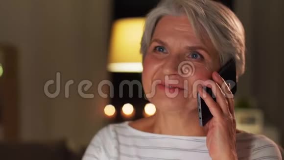 一位老太太晚上在家打智能手机视频的预览图
