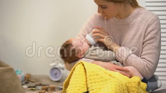 年轻的女士让小男孩睡觉用婴儿配方奶粉从瓶子里喂食视频的预览图