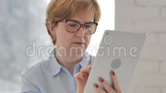 老女人使用平板电脑和应对项目失败视频的预览图