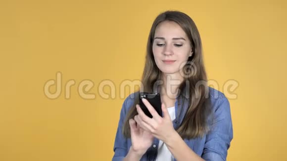 黄色背景下智能手机应用成功的美女视频的预览图