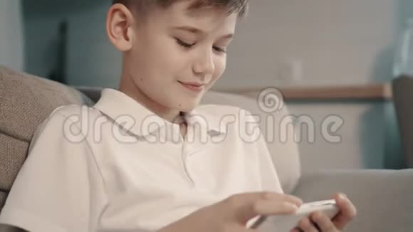 男孩坐在沙发上用智能手机特写视频的预览图