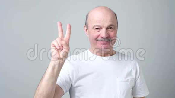 老人举起两个手指显示和平或胜利的象征视频的预览图