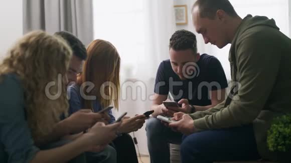 快乐的朋友群使用电话坐在沙发上室内大笑谈笑风生视频的预览图