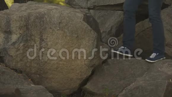 微笑的年轻人坐在大石头上野外露营享受冒险视频的预览图
