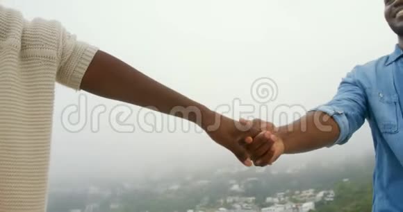 中段非裔美国夫妇手牵手在海滩散步4k视频的预览图