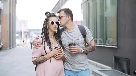 一对时髦的男人和孕妇在城里边喝咖啡边说话视频的预览图