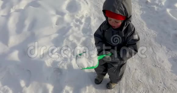 脸颊红红的小男孩舀起雪来视频的预览图