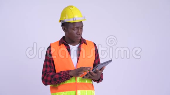 年轻快乐的非洲男性建筑工人思考使用数字平板电脑视频的预览图