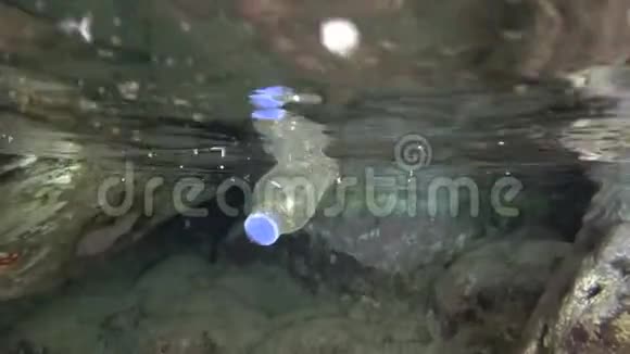 塑料污染水下分裂水平一个塑料瓶漂浮在洞穴里的水面上水下射击视频的预览图