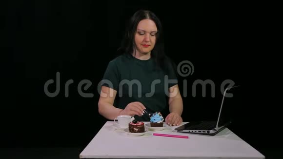 一个黑发女人在咖啡馆的餐桌上喝咖啡吃甜点蛋糕视频的预览图